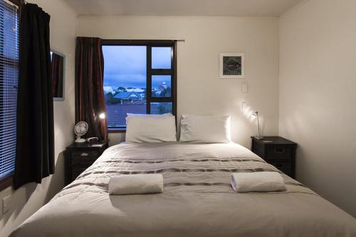 a bedroom with a large bed with a window at DOLLY KIWI ICONIC BACH IN PRIME LOCATION in New Plymouth