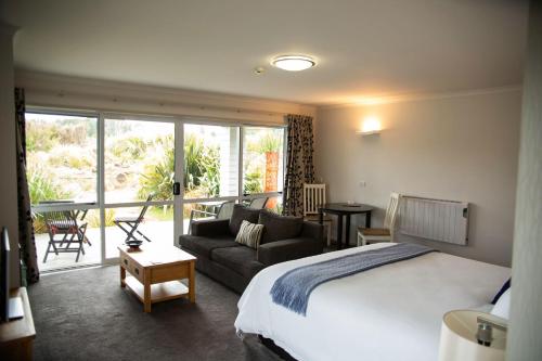 Tongariro Suites في أوهاكيون: غرفة نوم مع سرير وغرفة معيشة مع أريكة