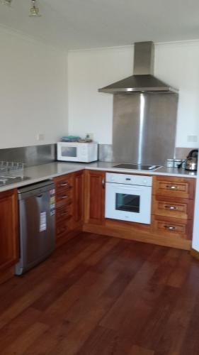 a kitchen with wooden cabinets and a white stove top oven at St Helens On The Bay in St Helens