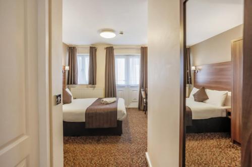 a hotel room with two beds and a mirror at Prince Regent Hotel Excel London in London
