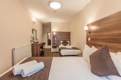 a hotel room with two beds and a desk at Prince Regent Hotel Excel London in London