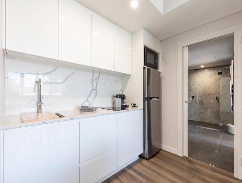La cuisine blanche est équipée d'un évier et d'un réfrigérateur. dans l'établissement Sleek, modern and comfortable on Hastings Street, à Noosa Heads