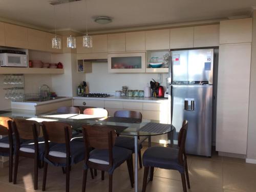 cocina con mesa, sillas y nevera en Laguna Bahía Algarrobo edificio Océano 406, en Algarrobo