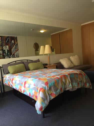 a bedroom with a bed and a couch and a mirror at Flinders Street 238, CLEMENTS HOUSE at Federation Square, Melbourne, Australia in Melbourne