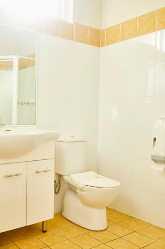 a white bathroom with a toilet and a sink at Town and Country Motel in Sydney