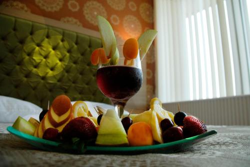 a plate of fruit with a glass of red wine at Lounge Hotel in Tuzla
