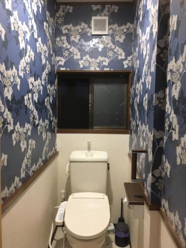 a bathroom with a toilet with blue and white wallpaper at Guest House Hostel yukuru in Iiyama