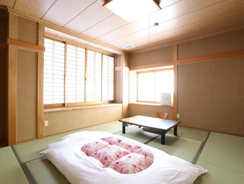 a room with a bed and a table in it at Asahikan in Shiojiri