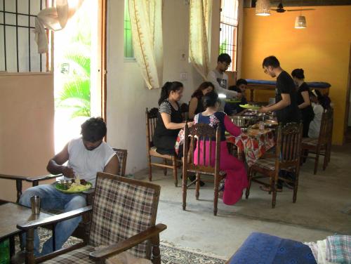 a group of people sitting at a table in a restaurant at Holiyday in VGF Farm House in Dānishpet