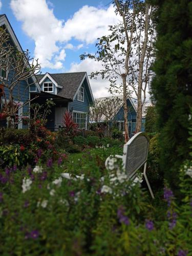 a yard with a bench in front of a house at Baan JaoKorKluay บ้านเจ้ากอกล้วย in Chiang Rai