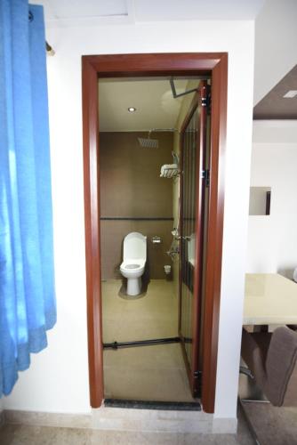 a bathroom with a toilet and a glass door at Sky Residency in Chennai