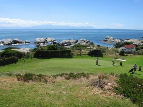people playing golf on a golf course near the ocean at Porcupine Walk in Simonʼs Town