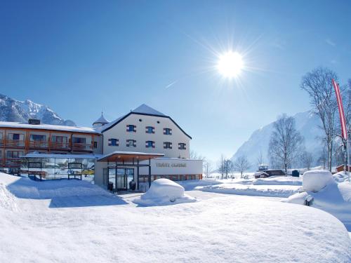 a building covered in snow with the sun behind it at aja Fürstenhaus am Achensee in Pertisau