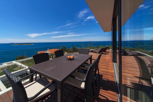 a table and chairs on a balcony with a view of the ocean at Golden Rays Luxury Villas & Apartments in Primošten