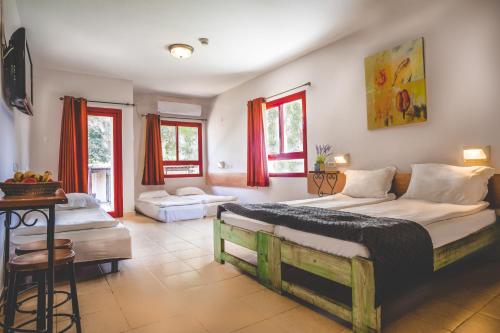 a bedroom with two beds and a table and windows at Mashabei Sade Kibbutz Country Lodging in Mashabbe Sade