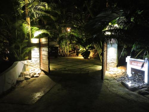 a gate to a garden at night with palm trees at Bois Joli in Mahe