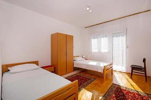 1 dormitorio con 2 camas, armario y silla en Josip, en Kaštela