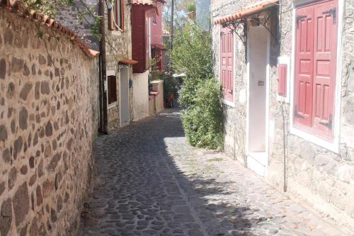an alley in an old town with red doors at ΜΑΧΗ Ενοικιαζόμενα δωμάτια in Mithymna