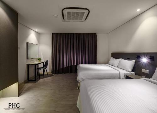 a hotel room with two beds and a desk at Magazine Vista Hotel by PHC in George Town