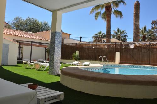 un patio trasero con piscina y un patio con mesas en Apartamentos Acuario, en Denia