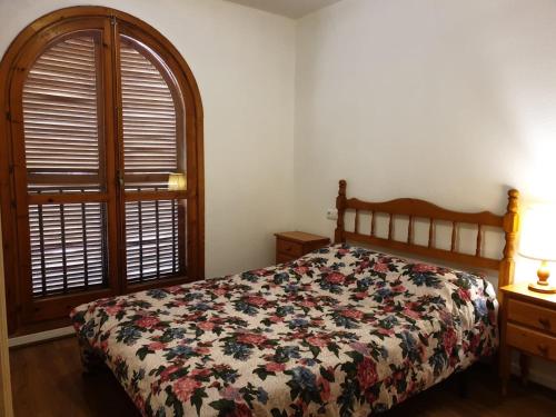 1 dormitorio con 1 cama con colcha de flores y ventana en Calle Rafal, en Torrevieja