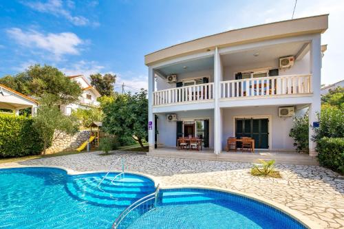 a villa with a swimming pool in front of a house at Villas Kampor in Kampor