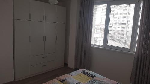 a bedroom with a white cabinet and a window at Roza Apartment in Varna City