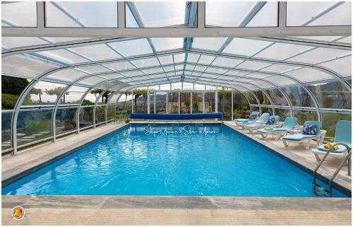 a swimming pool with a glass roof with chairs and a pool at B&B Villa Vale Flores in Viana do Castelo