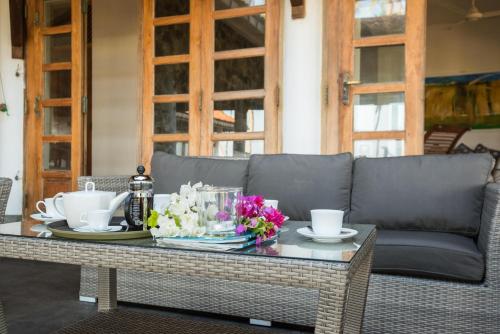 a table with a couch and flowers on it at Jetwing Kottukal Beach House in Arugam Bay
