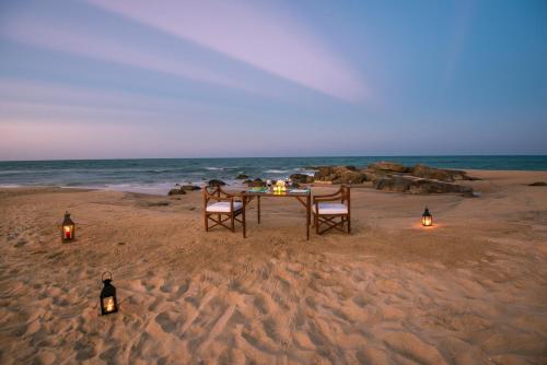 a table and chairs on the beach with lights at Jetwing Kottukal Beach House in Arugam Bay