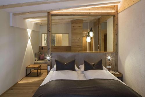 a bedroom with a large bed with a large mirror at Falkensteiner Hotel & Spa Falkensteinerhof in Valles