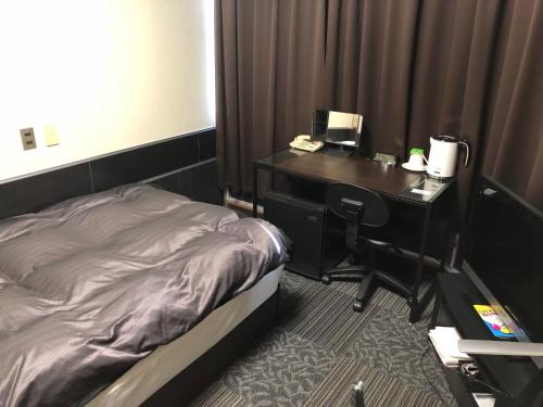 a bedroom with a desk with a bed and a desk sidx sidx sidx at Business Stay in Satsumasendai