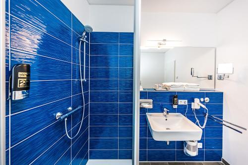 a blue tiled bathroom with a sink and a shower at Best Western Plus Royal Suites in Leipzig