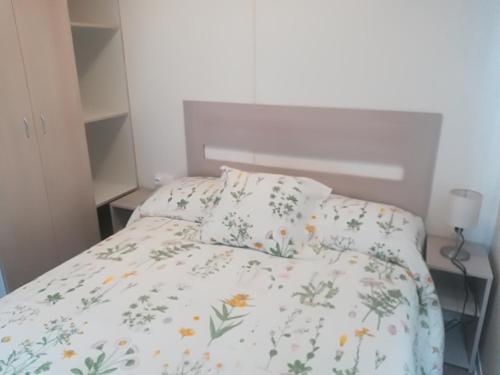 Una cama con una colcha blanca con flores. en CAMPING BAHIA SANTA POLA en Santa Pola