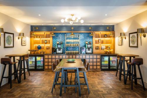 a bar with stools and a table in a room at Castle Hotel Windsor in Windsor