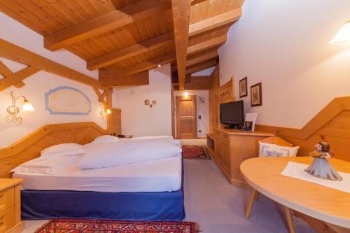 ein Schlafzimmer mit einem großen Bett und einem Tisch in der Unterkunft Malga Ces in San Martino di Castrozza