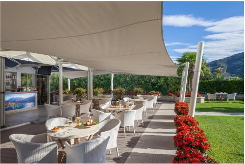 a restaurant with white tables and white chairs and flowers at Hotel Savoy Palace - Tonelli Hotels in Riva del Garda