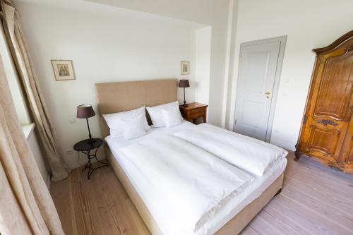 a bedroom with a large bed with white sheets at Hotel Gut Klostermühle natur resort & medical spa in Alt Madlitz