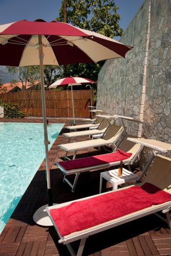 a row of lounge chairs with umbrellas next to a swimming pool at Hotel Villa Smeralda in Malcesine