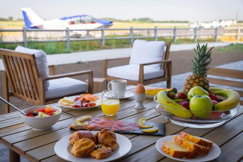 a wooden table topped with plates of food and fruit at Najeti Hôtel Lille Nord in Bondues