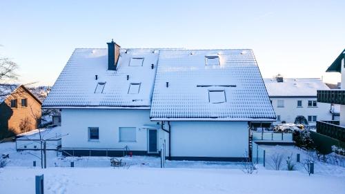 a white house with snow on the roofs at Apartment Schanzenstraße 690 m ü. M in Winterberg