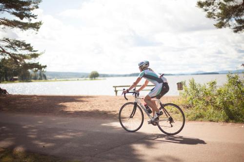 a person riding a bike on a path near a lake at First Camp Orsa - Dalarna in Orsa