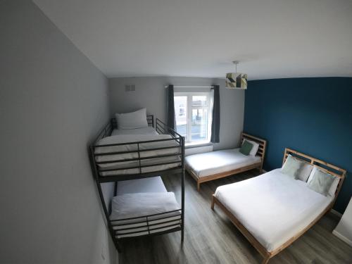 a room with three bunk beds and a window at Rougey Lodge Hostel in Bundoran