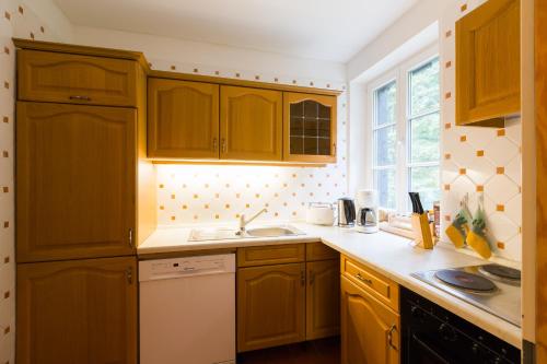 a kitchen with wooden cabinets and a sink and a window at Hotel Gut Klostermühle natur resort & medical spa in Alt Madlitz
