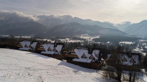 a group of houses covered in snow on a mountain at Osada Kościelisko - Tatry na Wyciągnięcie Ręki in Kościelisko