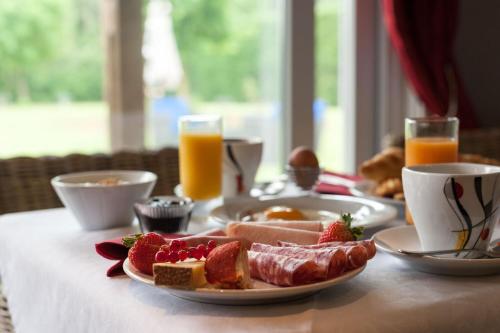 a table with a plate of breakfast foods and orange juice at Les Jardins d'Ulysse, The Originals Relais in Stella-Plage