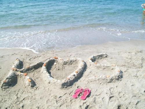 a pair of pink flip flops in the sand on the beach at Ellie's in Kardamaina