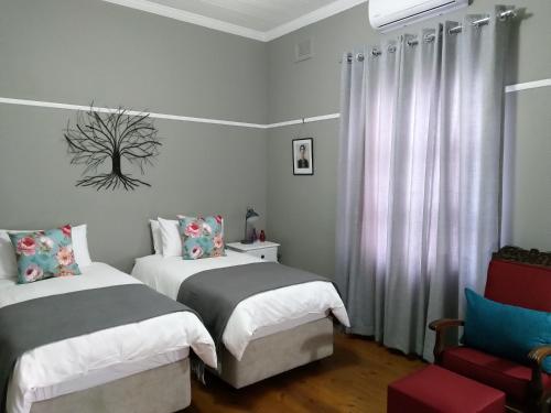1 dormitorio con 2 camas y 1 silla en Casa Mia en Pietermaritzburg