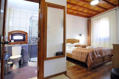 ein Schlafzimmer mit einem Bett und ein Badezimmer mit einer Dusche in der Unterkunft Pensiunea Manidum in Buşteni