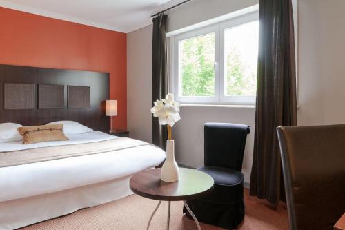 a bedroom with a bed and a vase with flowers on a table at Les Jardins d'Ulysse, The Originals Relais (Relais du Silence) in Stella-Plage